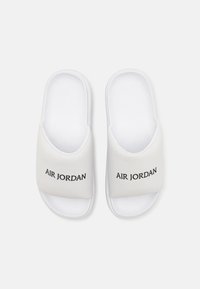 White slide sandals with a soft synthetic upper, featuring embossed "AIR JORDAN" branding on the strap and a textured white footbed.
