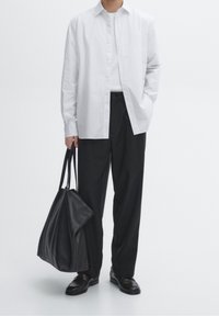Chemise blanche à rayures boutonnée, pantalon noir, sac en cuir noir et chaussures noires. Design minimaliste avec textures lisses.