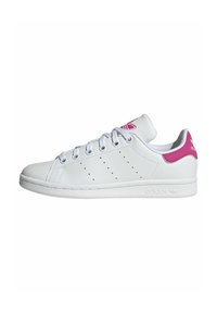 White leather sneaker with pink accent on the heel, featuring a rounded toe, six eyelets, and perforated side detailing.