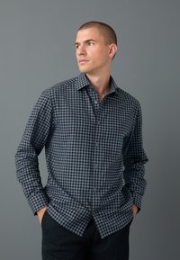Camicia da uomo a maniche lunghe con motivo a quadri nero e grigio, colletto con bottoni e bottoni frontali. Realizzata in tessuto leggero.