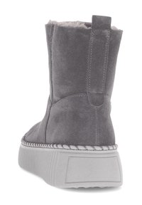 Botte de cheville en suede gris avec une doublure intérieure douce, une épaisse semelle blanche et des coutures décoratives le long du bord. Comprend une languette de tirage à l'arrière.