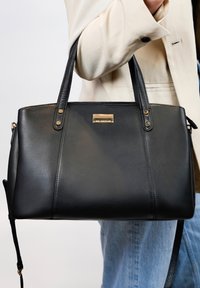 Zwarte leren handtas met twee bovenhandvatten, gouden accenten en een rechthoekige vorm. Beschikt over een gestructureerde afwerking en een bijgeleverde schouderriem.