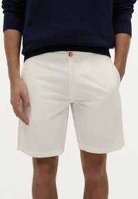 Hvide shorts lavet af et glat stof, med knaplukning og sidelommer. Kanten er ren og lige, og pasformen er afslappet.
