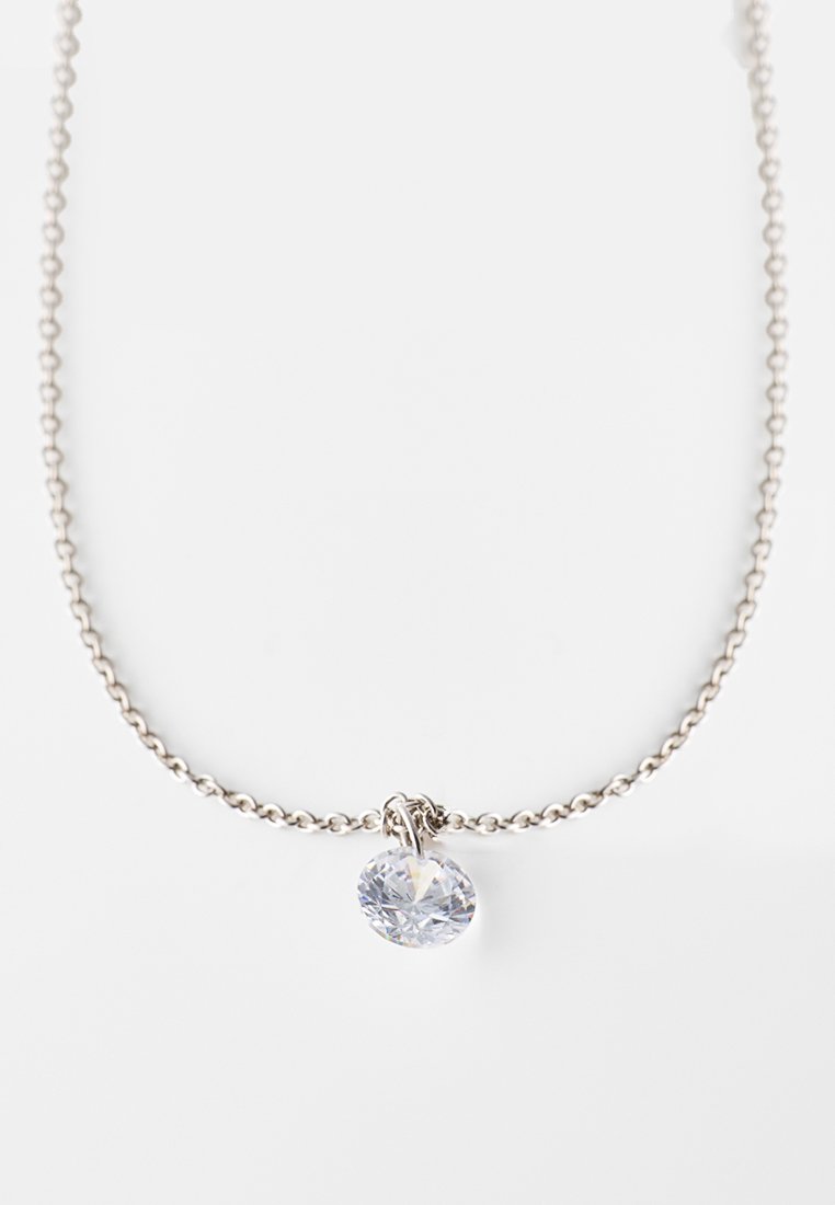 Collar de cadena de plata con un colgante ovalado de gema clara. La cadena tiene una textura con pequeños eslabones, y el colgante presenta facetas intrincadas.