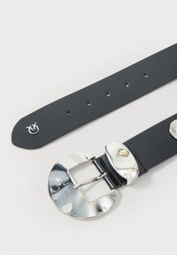 Cinto de couro preto com uma grande fivela circular polida em tom prateado e vários buracos de ajuste ao longo da cinta.