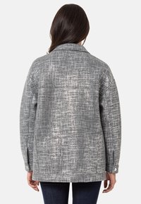 Grau gemusterte Jacke mit einer strukturierten Oberfläche, die einen Kragen, Knopfmanschetten und einen lockeren Schnitt aufweist. Die Rückansicht zeigt das Design deutlich.
