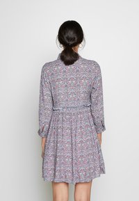 Langärmliges Kleid aus leichtem Stoff mit einem floralen Muster in Pink, Blau und Weiß. Geraffte Taille und knielanger Saum.