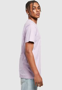 Purple cotton t-shirt with short sleeves and a crew neckline, featuring a relaxed fit and plain design, worn with light blue jeans.