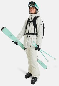 Skiausrüstung umfasst eine weiße Jacke, schwarze Hose, schwarze Handschuhe und schwarze Skischuhe. Die Ski sind hellblau mit einem gesprenkelten Muster, und die Stöcke sind türkis.