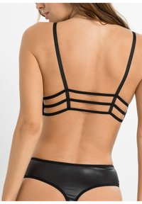 Bralette noire avec des fines bretelles et un design de dos géométrique avec plusieurs bandes horizontales. Matériau noir lisse et brillant avec un slip assorti.
