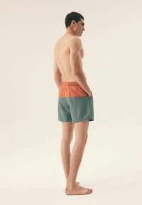 Męskie szorty pływackie z podzielonym wzorem: pomarańczowa górna część, turkusowa dolna część, elastyczny pasek w talii, boczne kieszenie oraz lekki materiał.