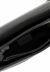 Schwarze, strukturierte Ledertasche mit einem Reißverschluss. Das Innere verfügt über ein schwarzes Futter und eine zusätzliche Reißverschluss-Tasche zur Organisation.