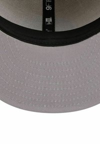 Casquette de baseball grise avec une visière noire, présentant un tissu texturé et un motif cousu. L'étiquette intérieure indique la marque et la taille.