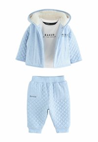 Giacca trapuntata blu chiaro con fodera in pelliccia bianca, abbinata a pantaloni joggers blu coordinati. Presenta una stampa del logo sulla maglia e sui pantaloni.