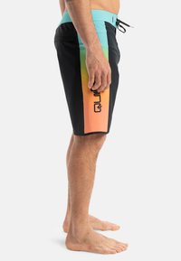 Bañador negro con un diseño degradado en naranja y amarillo, con una cintura turquesa y un logo negro en el lateral.