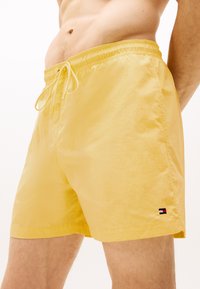 Shorts de bain jaunes avec une taille élastique et un cordon de serrage. Fabrication en tissu texturé et petit logo multicolore sur l'ourlet.