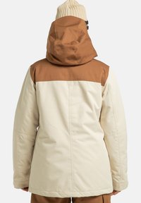 Dwukolorowa kurtka zimowa z brązową górną częścią i kremową dolną częścią, wyposażona w kaptur i o gładkiej fakturze tkaniny.
