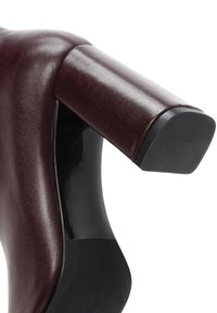 Gros plan sur un talon bloc en cuir marron foncé avec une semelle extérieure texturée noire sur une chaussure habillée pour femme.