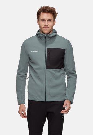 Mammut fleece jacket in muted teal with a black chest pocket, hood, and zipper closures, featuring a textured finish for warmth.