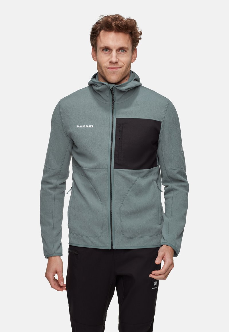 Mammut Fleecejacke in gedämpftem Blaugrün mit einer schwarzen Brusttasche, Kapuze und Reißverschluss, ausgestattet mit einer strukturierten Oberfläche für Wärme.