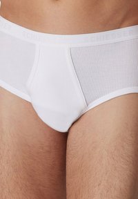 Weiße Baumwollslips mit gerippter Textur und elastischem Bund mit "SCHIESSER"-Branding. Klassischer Schnitt, enganliegende Passform und minimalistisches Design.