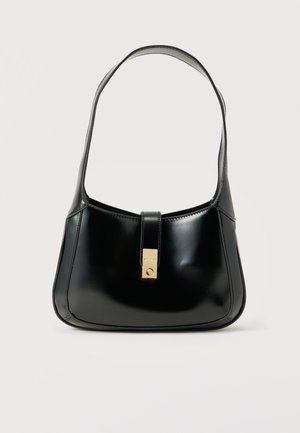 Schwarze, glänzende Lederhandtasche mit einem einzelnen Schulterriemen und einem zentralen goldfarbenen rechteckigen Verschluss vor schlichtem hellem Hintergrund.