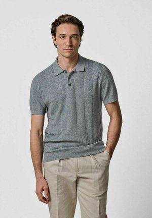 Polo grigia a maniche corte con un sottile motivo a spina di pesce, colletto a costine e patta con tre bottoni, abbinata a pantaloni di colore chiaro.