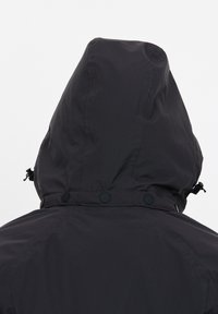 Schwarze Kapuzenjacke mit glatter Textur, ausgestattet mit Schnappverschlüssen und Toggle-Verschlüssen am Hals, entworfen für Funktionalität und Wärme.