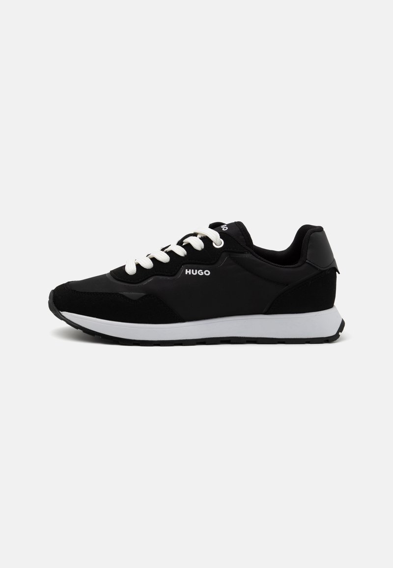 Baskets basses noires avec lacets blancs, semelle blanche et logo "HUGO" sur le côté, vues de l'extérieur.