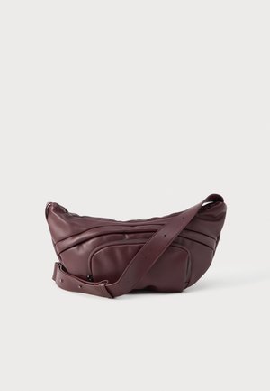 Sac bandoulière en cuir marron foncé avec bandoulière réglable et poche avant zippée sur fond clair uni.
