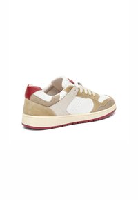 Baskets beige et blanches avec des accents rouges, en suède et cuir, design basse, surfaces texturées et semelle en caoutchouc.