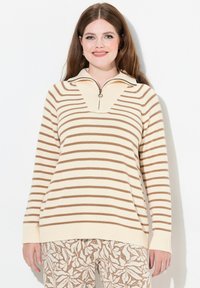 Beiger und brauner gestreifter Pullover mit einem Reißverschlusskragen, gerippten Bündchen und einer lockeren Passform, kombiniert mit gemusterten beigen Hosen.