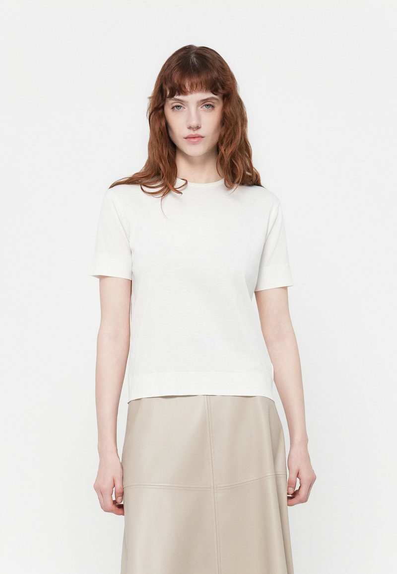Witte T-shirt met korte mouwen en ronde halslijn, afgewerkt met ribgebreide cuffs, gemaakt van zachte, lichte stof, gecombineerd met een beige gestructureerde rok.