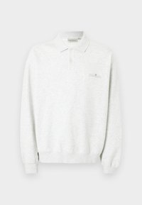 Πουκάμισο πόλο λευκό με μακρύ μανίκι, δύο κουμπιά και ριμπ μανσέτες, με διακριτικό κεντημένο λογότυπο στο στήθος.