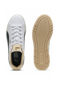 Hvide sneakers med en glat læderoverdel, grønne sideaccenter og en struktureret gummisål med et zigzag-mønster. Branding på tungen.