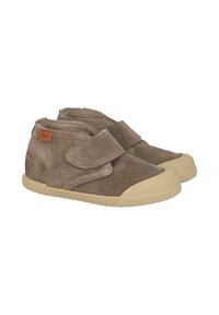 Zapatos infantiles de ante marrón con una tira de velcro, puntera redondeada y suela de goma beige. Cuenta con una etiqueta de logotipo naranja en el lateral.