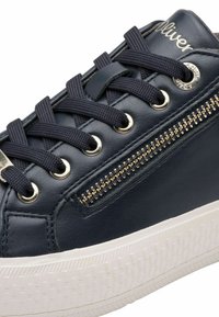 Marineblauwe leren sneaker met gouden accenten, ronde neus, witte rubberen zool en decoratieve zijrits. Textuur oppervlak met vetersluiting.