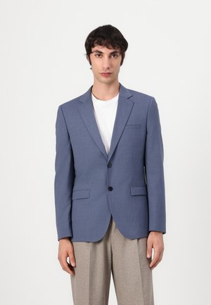 Blå blazer laget av teksturert stoff, med to frontlommer, en enkel knappelukking og en slim fit-design. Kombinert med en hvit skjorte.