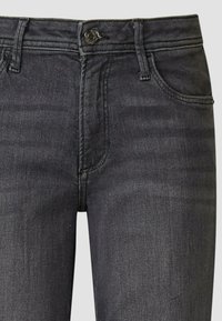 Ciemnoszare dżinsy z denimu z zamkiem błyskawicznym, zapięciem na guzik, czterema kieszeniami i subtelnym blaknięciem w fakturze tkaniny.