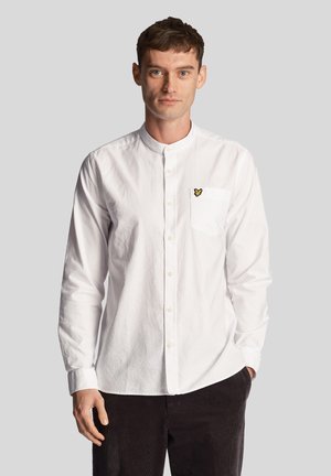 Camicia bianca con colletto alla mandarino, dotata di taschino sul petto e dettagli di logo giallo. Ha un tessuto testurizzato e maniche lunghe.