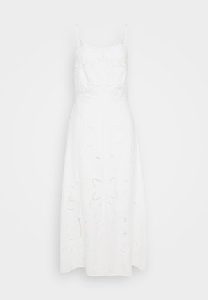 Biała lniana sukienka z regulowanymi ramiączkami spaghetti, zdobiona haftem kwiatowym i wycięciami na spódnicy. Sylwetka w kształcie litery A.
