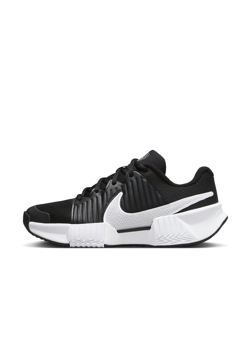 Scarpe sportive in bianco e nero con tomaia in rete, design a coste, collo imbottito e suola in gomma con un motivo testurizzato.