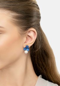 Blue flower-shaped earrings with textured petals, adorned with rhinestones, featuring a single white pearl accent below.