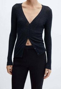 Zwarte geribbelde cardigan met lange mouwen, V-hals en knopen aan de voorkant. De stof lijkt zacht met een lichte glans en een slim-fit ontwerp.