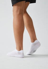 Witte enkelkousen met een textuurdesign en geribde boorden; vanuit de zijaanzicht bekeken, die een stevige pasvorm en midfoot bedekking toont.