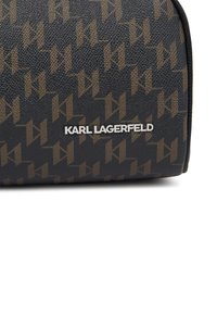 Funda negra texturizada con un patrón de logotipos marrones repetitivos y la marca "KARL LAGERFELD" en plata en la parte frontal, con bordes redondeados.