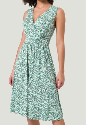 Zielona sukienka bez rękawów z białym kwiatowym wzorem, kopertowym dekoltem w serek, dopasowaną talią i rozkloszowaną spódnicą do kolan.