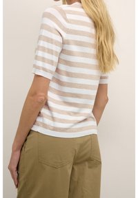 Top de punto de manga corta con rayas horizontales en beige claro y blanco. Cuello redondo y textura suave. Combinado con pantalones caqui.