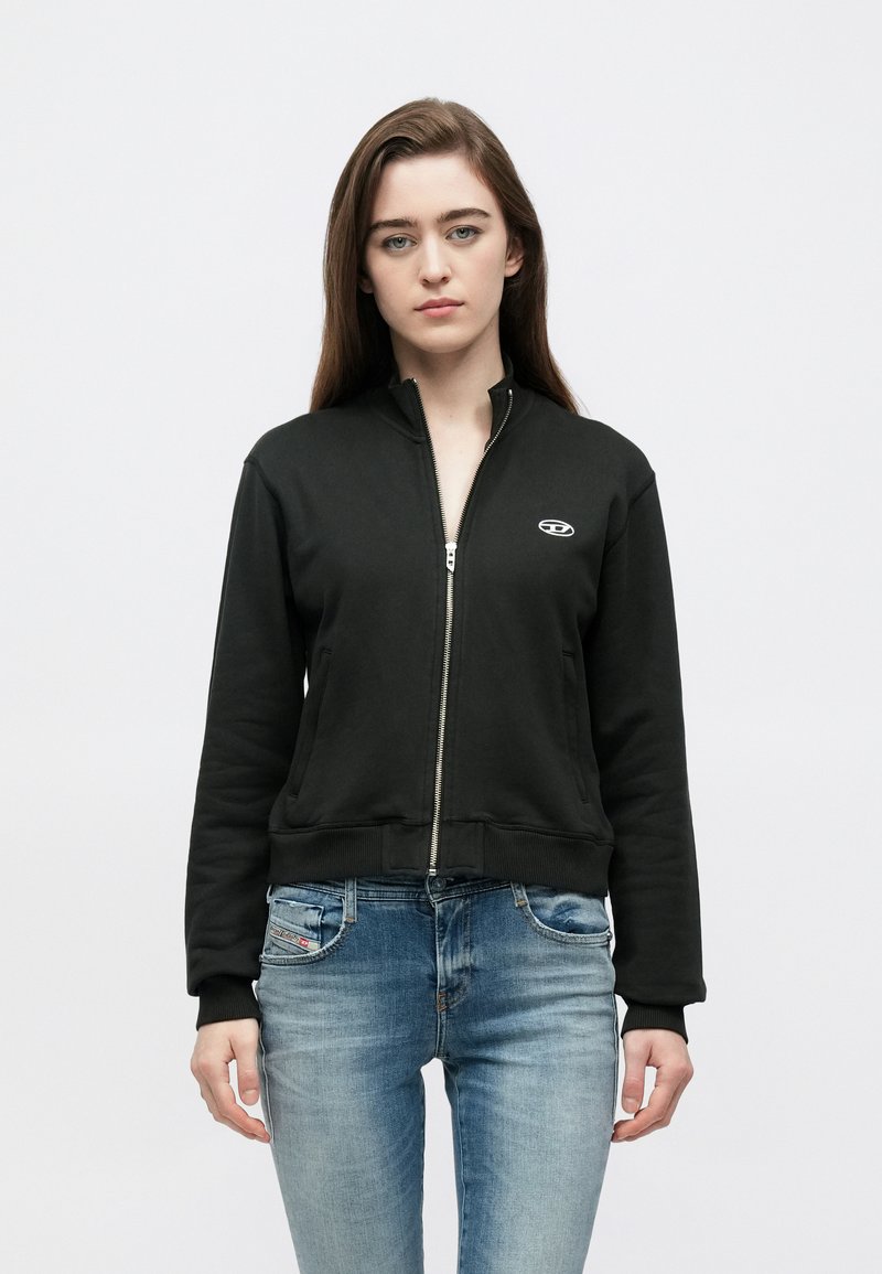 Μαύρο φούτερ με φερμουάρ από απαλό υλικό, με ψηλό γιακά και ριμπ μανσέτες. Διαθέτει μικρό λογότυπο στο στήθος και μπροστινές τσέπες.