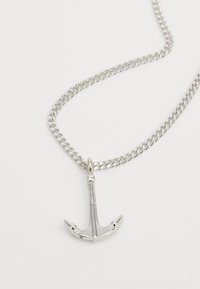 Collier en chaîne en argent avec un pendentif en forme d'ancre détaillé, finition métallique polie et design classique, mettant en valeur son thème nautique.